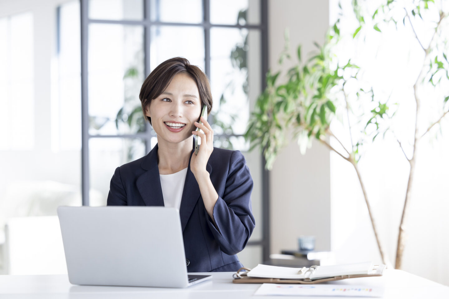 自宅のデスクでPCとスマホを使って働く女性。DX化が進む中で、事務職の働き方やスキルが変わりつつある様子を表現した写真。